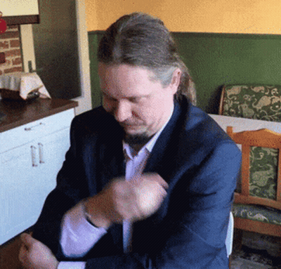 A Man With Long Hair And A Beard Is Sitting At A Table GIF