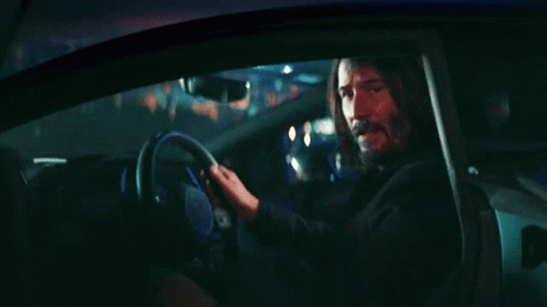 A Man With Long Hair And A Beard Is Sitting In A Car At Night GIF