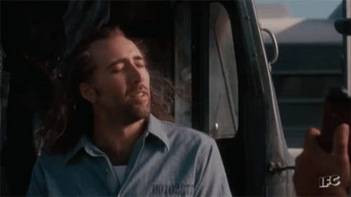 A Man With Long Hair And A Beard Is Sitting In A Car With His Eyes Closed And Smiling . GIF