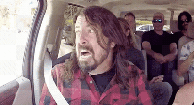A Man With Long Hair And A Beard Is Sitting In A Car With Other People . GIF