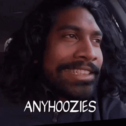 A Man With Long Hair And A Beard Is Sitting In A Car With The Words Anyhoozies On His Face . GIF