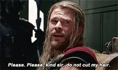 A Man With Long Hair And A Beard Is Sitting In A Chair And Talking To Another Man . GIF