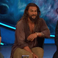 A Man With Long Hair And A Beard Is Sitting In A Chair On A Stage . GIF