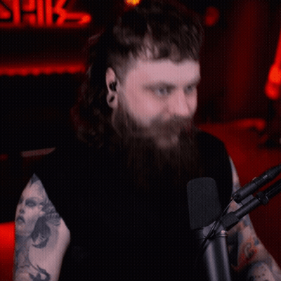 A Man With Long Hair And A Beard Is Sitting In Front Of A Microphone GIF