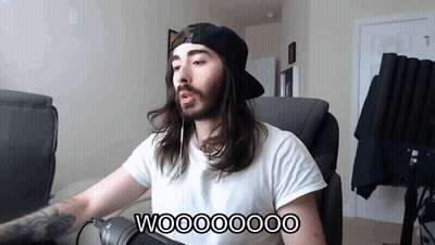 A Man With Long Hair And A Beard Is Sitting In Front Of A Microphone With The Words Wooooooo On The Bottom GIF