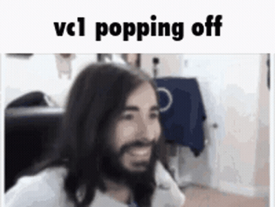 A Man With Long Hair And A Beard Is Smiling While Sitting In A Chair . GIF
