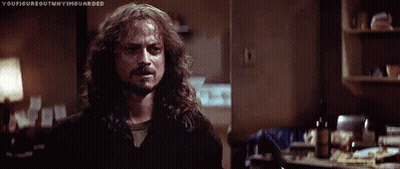 A Man With Long Hair And A Beard Is Standing In A Dark Room In A Kitchen . GIF