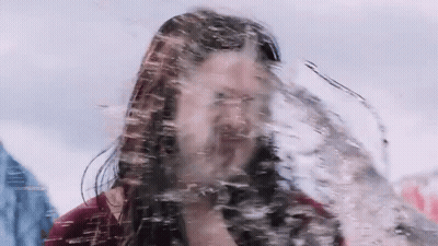 A Man With Long Hair And A Beard Is Standing In A Pool Of Water . GIF