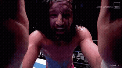 A Man With Long Hair And A Beard Is Standing In A Ring With His Arms In The Air . GIF