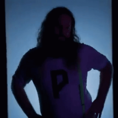 A Man With Long Hair And A Beard Is Standing In Front Of A Blue Background . GIF