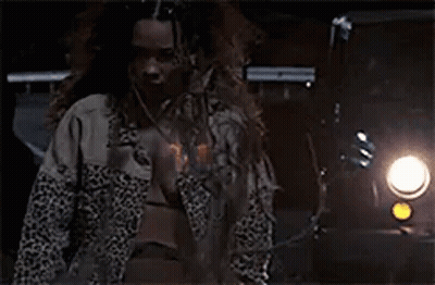 A Man With Long Hair And A Beard Is Standing In Front Of A Car At Night . GIF