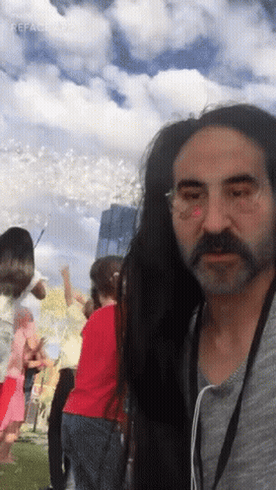A Man With Long Hair And A Beard Is Standing In Front Of A Crowd Of People GIF