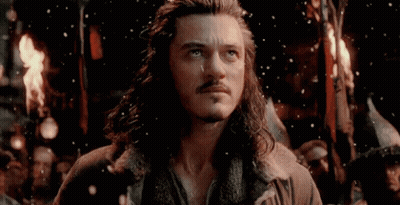 A Man With Long Hair And A Beard Is Standing In Front Of A Group Of People Holding A Torch . GIF
