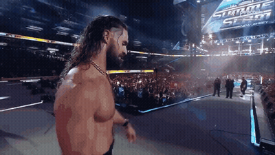 A Man With Long Hair And A Beard Is Standing In Front Of A Sign That Says Summerslam GIF