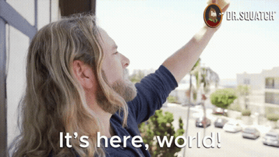 A Man With Long Hair And A Beard Is Standing On A Balcony With The Words " It 'S Here World " Above Him GIF