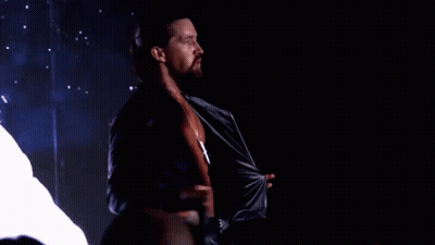 A Man With Long Hair And A Beard Is Taking Off His Shirt GIF