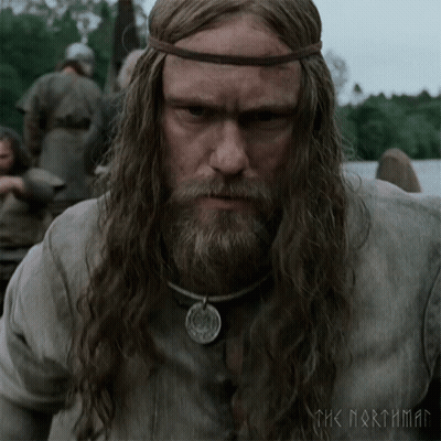 A Man With Long Hair And A Beard Is Wearing A Necklace And A Headband With The Words The Northman On It GIF