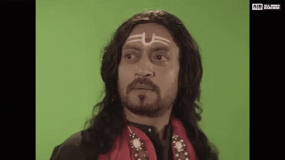 A Man With Long Hair And A Beard Is Wearing A Wig And A Headband With A Symbol On His Forehead . GIF