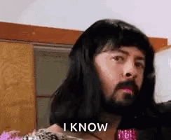 A Man With Long Hair And A Beard Is Wearing A Woman 'S Wig And Says `` I Know '' . GIF