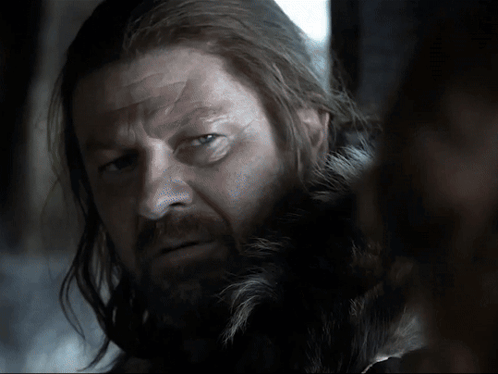 A Man With Long Hair And A Beard Looks At Something GIF