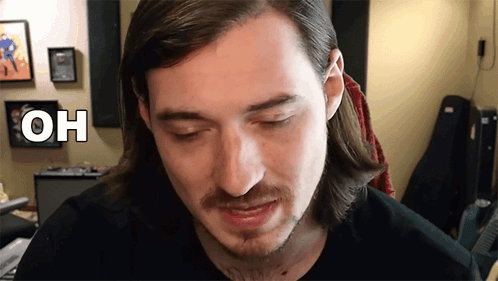 Man With Long Hair And Beard Looking At Camera With Oh Above Head GIF