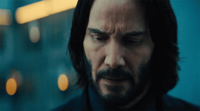 A Man With Long Hair And A Beard Looks Down At Something GIF