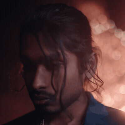 A Man With Long Hair And A Beard Looks Down At Something GIF