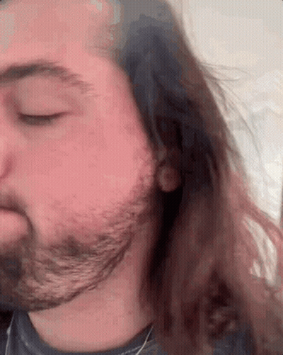 A Man With Long Hair And A Beard Looks Down With His Eyes Closed GIF