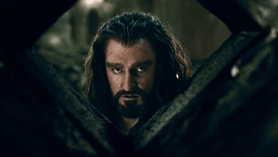 A Man With Long Hair And A Beard Looks Out Of A Window GIF
