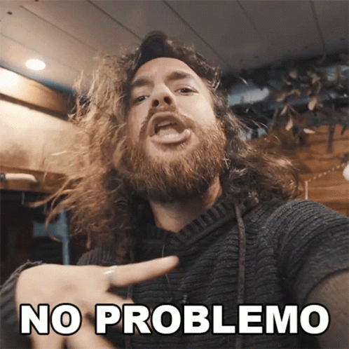 A Man With Long Hair And A Beard Pointing At The Camera With The Words No Problemo Below Him GIF