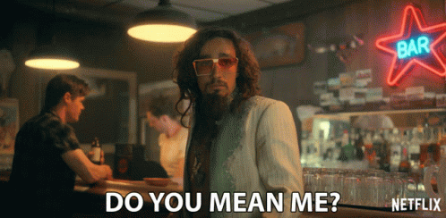 A Man With Long Hair And A Beard Stands In Front Of A Neon Sign That Says Bar GIF