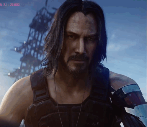 A Man With Long Hair And A Beard Stands In Front Of A Screen That Says R 21 22:03 GIF