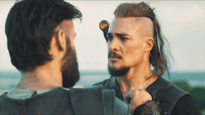 A Man With Long Hair And A Beard Stands Next To Another Man With Short Hair GIF