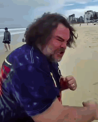 A Man With Long Hair And A Beard Stands On A Beach GIF