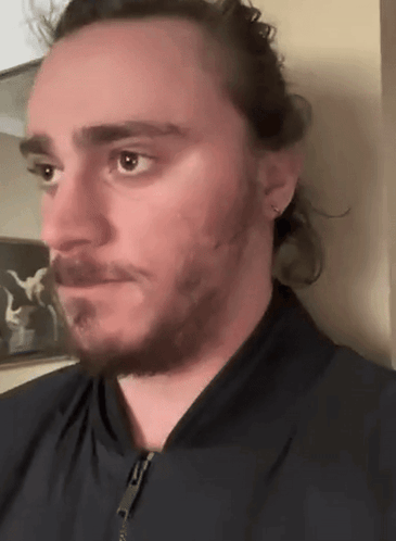 A Man With Long Hair And A Beard Wearing A Black Jacket GIF