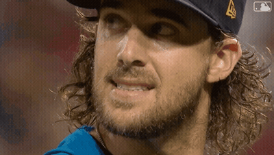 a man with long hair and a beard wearing a hat with a mlb logo on it