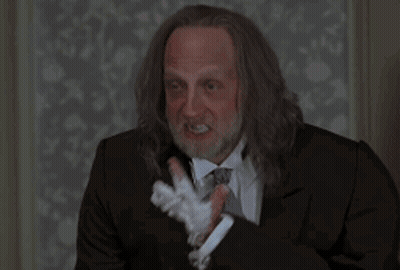 A Man With Long Hair And A Beard Wearing A Suit And Tie Smoking A Cigarette GIF
