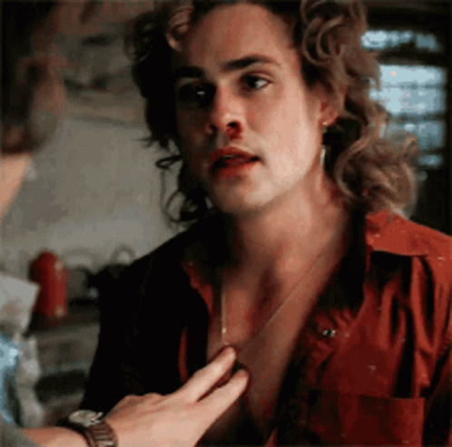 A Man With Long Hair And A Bloody Nose Is Being Touched By Another Man . GIF