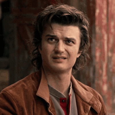 A Man With Long Hair And A Brown Jacket Is Making A Funny Face GIF