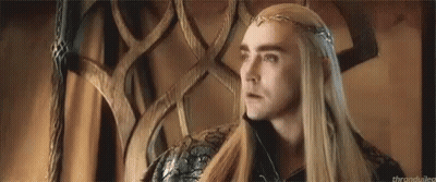 A Man With Long Hair And A Crown On His Head Is Sitting In A Chair . GIF