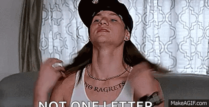 A Man With Long Hair And A Hat Is Sitting On A Couch In A Living Room . GIF