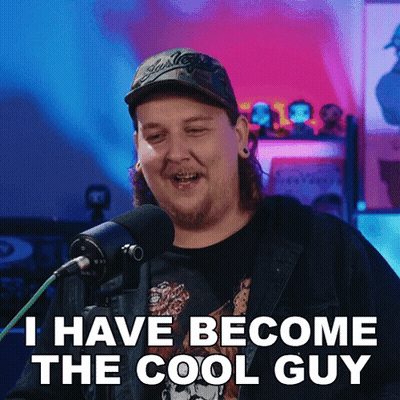 A Man With Long Hair And A Hat Says I Have Become The Cool Guy In Front Of A Microphone GIF