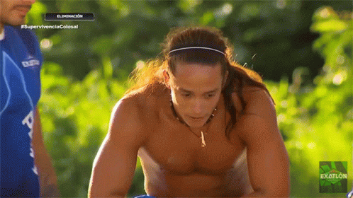 A Man With Long Hair And A Headband Is On A Television Screen That Says Exatlon GIF