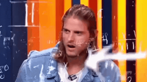 A Man With Long Hair And A Mullet Is Sitting In Front Of A Wall With Numbers Written On It . GIF