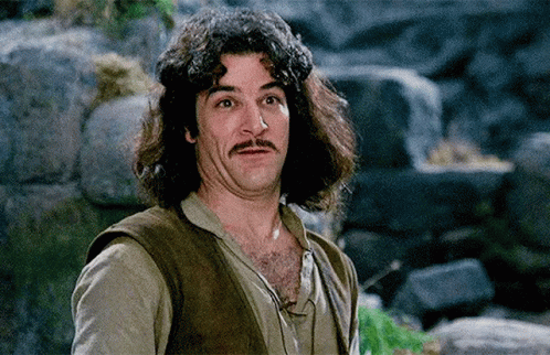 A Man With Long Hair And A Mustache Is Making A Face . GIF