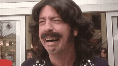 A Man With Long Hair And A Mustache Is Smiling GIF