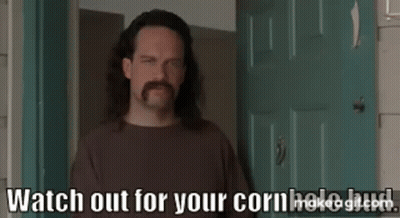 A Man With Long Hair And A Mustache Is Standing In Front Of A Door And Talking . GIF