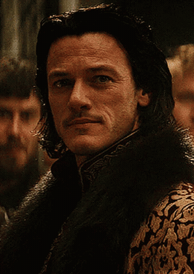 A Man With Long Hair And A Mustache Is Wearing A Fur Collar GIF