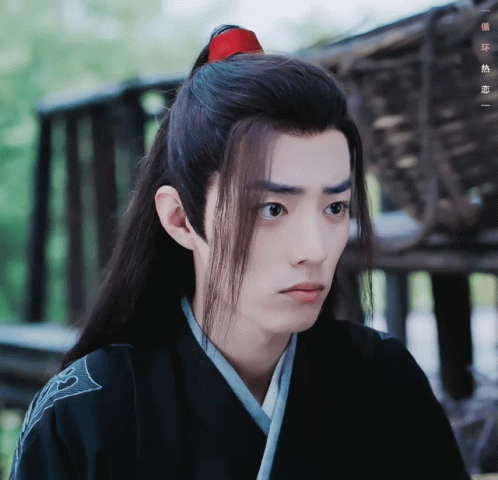 A Man With Long Hair And A Red Ponytail Looks To The Side GIF
