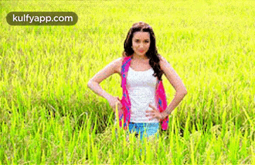 A Man With Long Hair And A Red Shirt Is Smiling In A Field . GIF